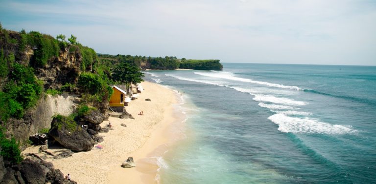 Waves rolling onto Balangan Beach in Bali beaches beneath limestone cliffs on the Bukit Peninsula