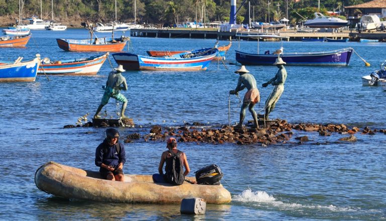 Traditional fishing boats and waterfront scene in Salvador Brazil with fishermen statues and calm bay waters