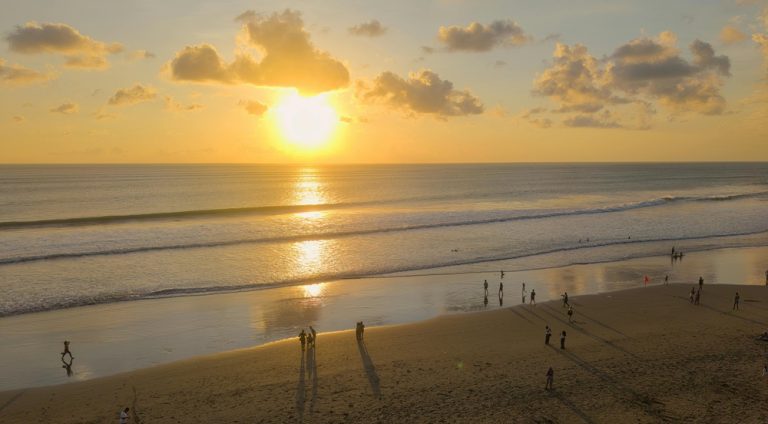 Golden sunset over the beach and ocean waves in Seminyak, Bali Caption: Description: