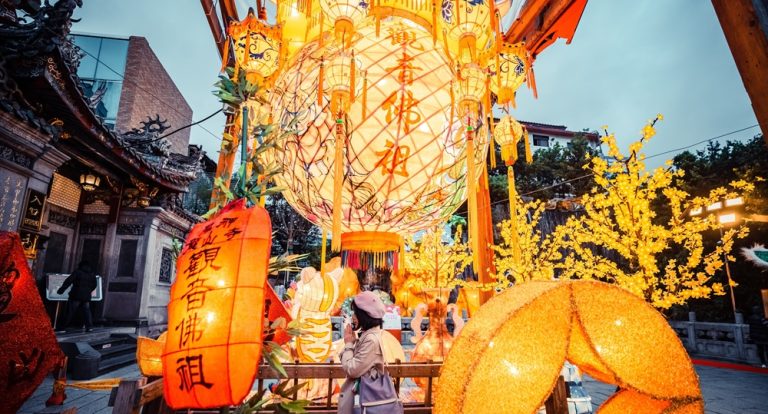 Traditional lantern festival decorations glowing outside a temple in Taipei at dusk Caption: Description: