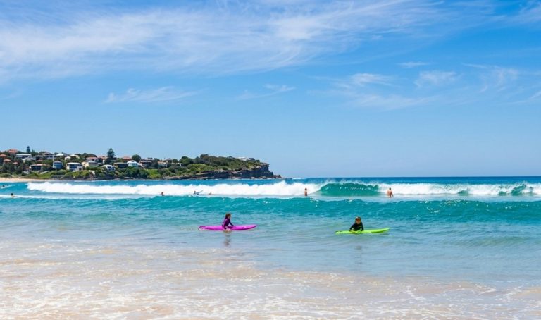 Surfers enjoying the waves at Manly Beach, one of the best surfing beaches in Sydney