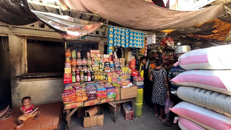 Petit marché couvert à Madagascar avec sacs de riz, épices, huiles et habitants faisant leurs courses
