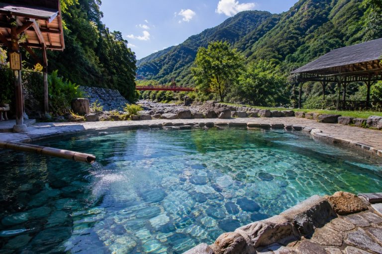 Taiwan hot springs in a mountain valley with clear geothermal pools, forested hills, riverside scenery, and outdoor onsen atmosphere