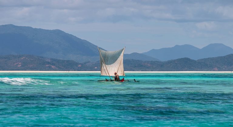 Pêcheur naviguant en pirogue traditionnelle sur un lagon turquoise à Madagascar