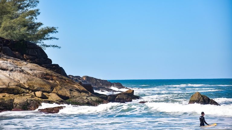 Rocky Atlantic coastline with waves and surfer near Santa Catarina Island in southern Brazil