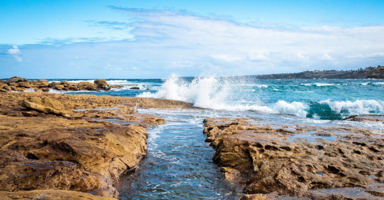 Ocean waves crashing against a rocky shoreline near the beaches in Sydney Australia