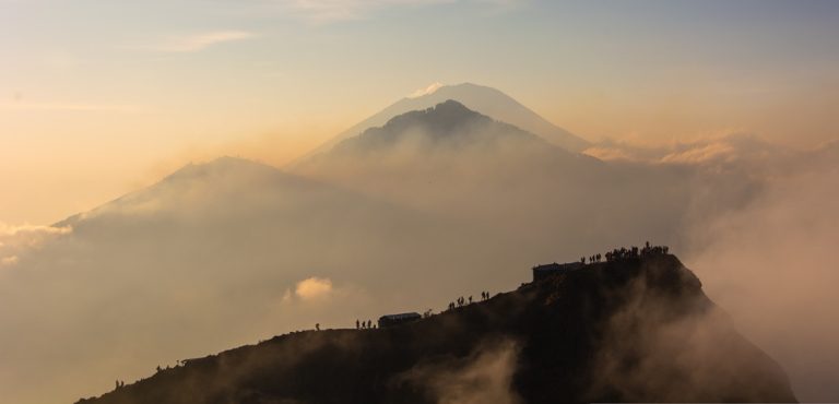 Sunrise view from Mount Batur volcano surrounded by clouds and mountain landscapes in Bali