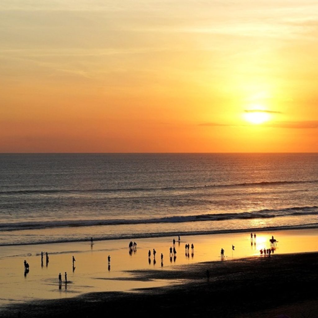 Sunset over Seminyak Beach showing travelers enjoying the shoreline during golden hour, illustrating how getting around Bali and explore its coastal destinations