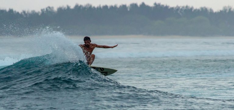Surfer riding a wave on the tropical coastline in Bali during a surf session Caption: Description: