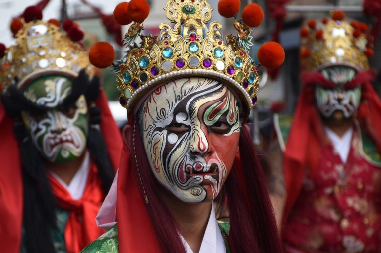 Traditional Taiwanese festival performers wearing ornate masks and costumes during a cultural parade - Taiwan travel budget guide