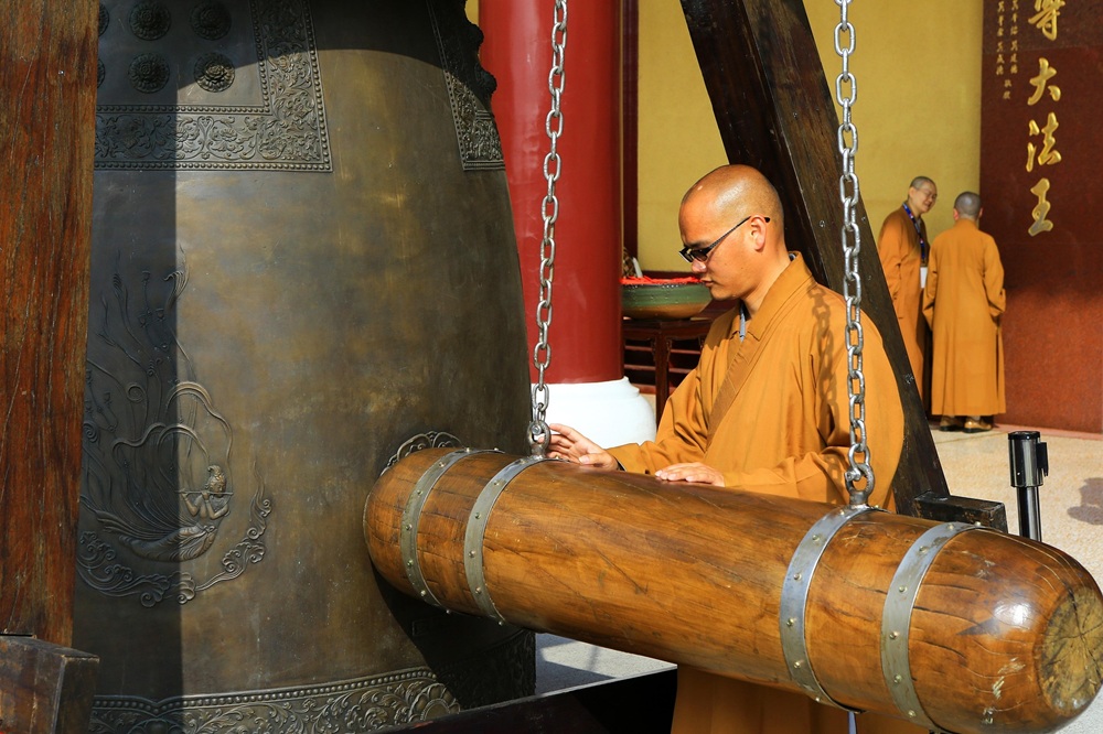 Taiwan Travel Budget Guide: Exploring Taiwan’s Temples Without Overspending Alt Text: Monk striking a large temple bell in Taiwan during a cultural ceremony - Taiwan travel budget guide