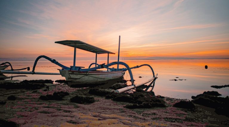 Traditional fishing boat resting on the shoreline at Lovina Beach during sunset in North Bali