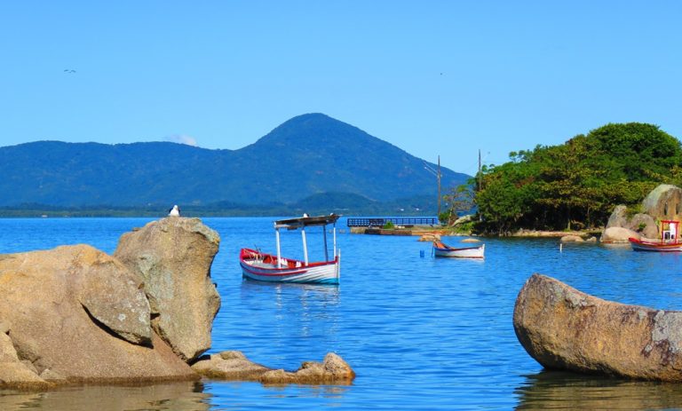 Traditional fishing boats floating near the rocky coastline of Santa Catarina Island in southern Brazil