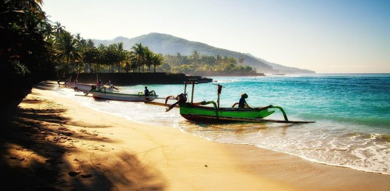 Traditional fishing boats resting on a tropical beach in eastern Bali, showing coastal destinations accessible when learning how to get around Bali Caption: Description: