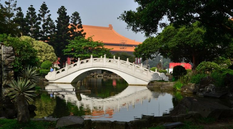 Traditional stone bridge and temple garden in Taipei surrounded by trees and water