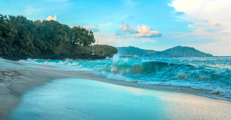 Pristine tropical beach with turquoise waves and white sand in Bali, highlighting Bali travel tips for choosing the right beaches and coastal areas Caption: Description: