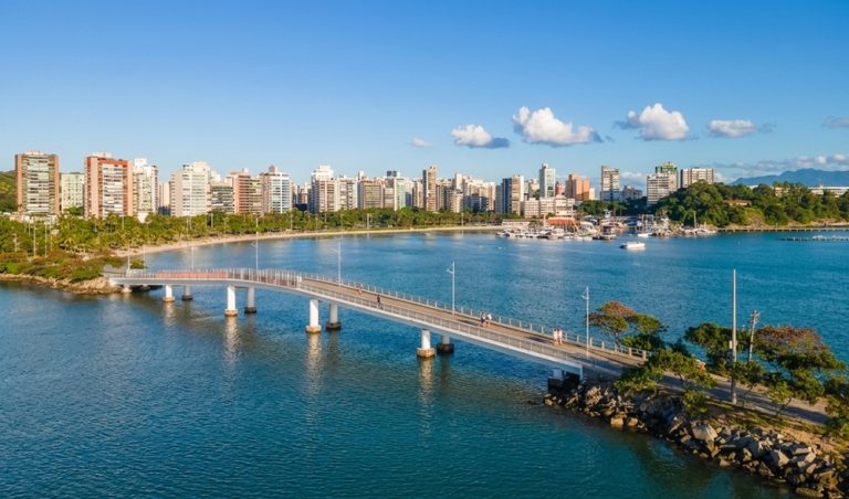 Modern waterfront skyline and bridge in Vitória Brazil with calm bay waters and blue sky Caption: Description: