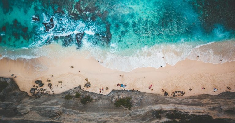 Best areas to stay in Bali featuring an aerial view of a stunning turquoise beach along Bali's southern coastline