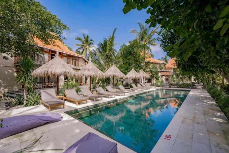 Swimming pool at Amrani Diamond Beach Villas & Pool in Nusa Penida surrounded by tropical gardens and thatched sun umbrellas