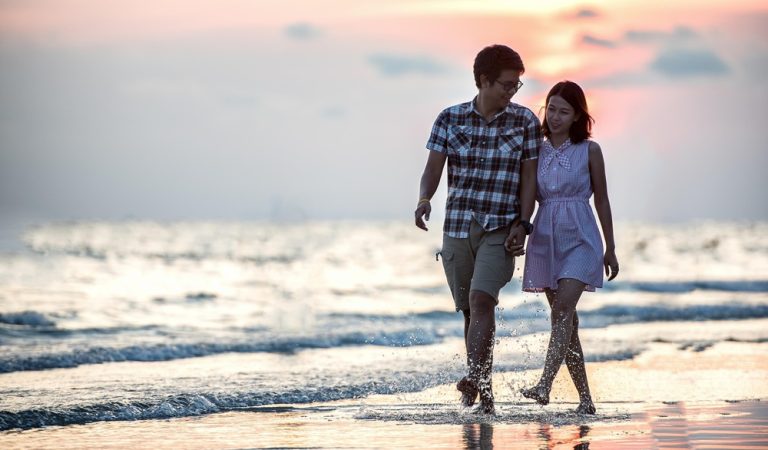 Couple enjoying a romantic sunset walk on the beach during a Bali honeymoon - Bali honeymoon guide
