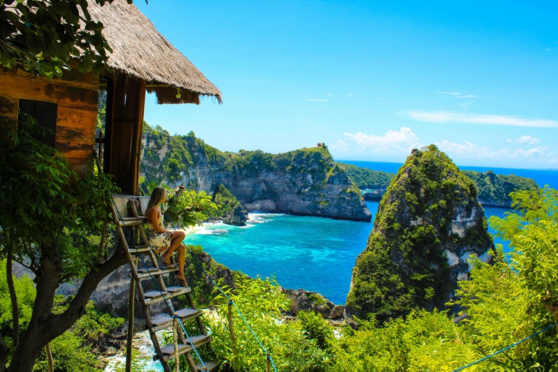Bali packing list traveler overlooking Nusa Penida coastline and turquoise ocean in Bali Indonesia