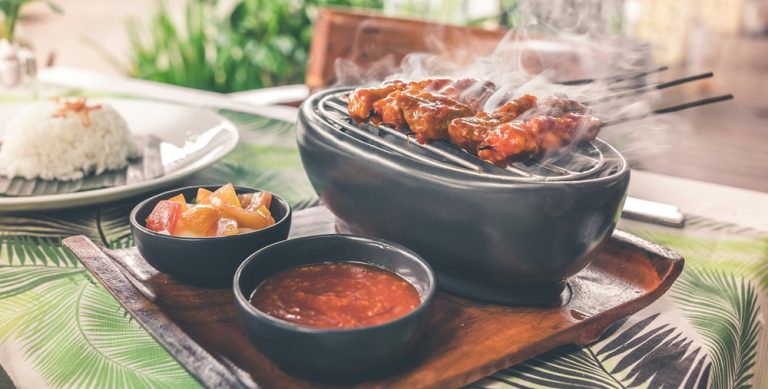 Food in Bali featuring freshly grilled sate skewers served with sambal sauce, rice, and traditional Balinese side dishes Caption Description