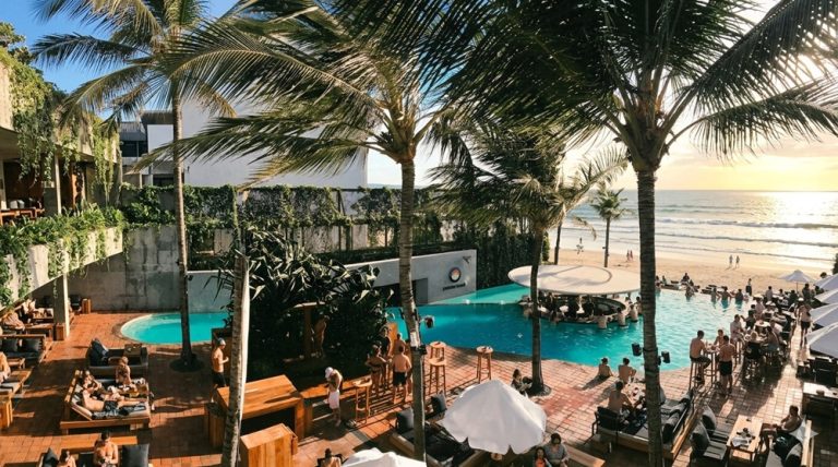 Visitors relaxing at a beachfront beach club overlooking the ocean in Seminyak, Bali