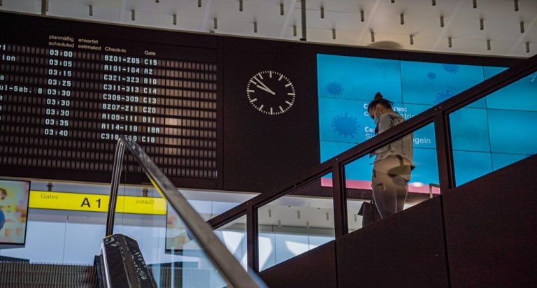 Bali airport guide showing a passenger checking flight information inside Ngurah Rai International Airport Caption Description