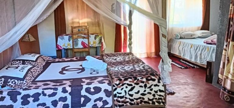 Chambre familiale de l'Ecolodge d'Isalo avec lits à baldaquin, moustiquaires et décoration traditionnelle malgache Légende : Description :