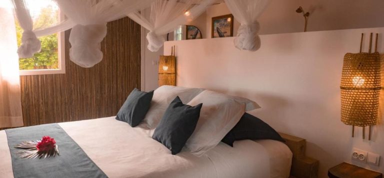 Chambre élégante des Bungalows Dicilaba à Sainte-Marie avec lit à baldaquin et décoration tropicale Légende : Description :