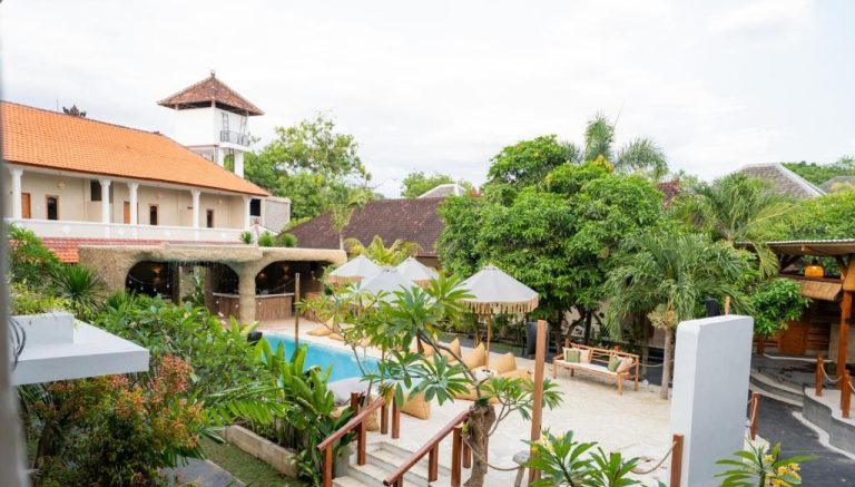 Courtyard and swimming pool area at Mad Monkey Uluwatu hostel in Bali, Indonesia, surrounded by tropical gardens and modern facilities.