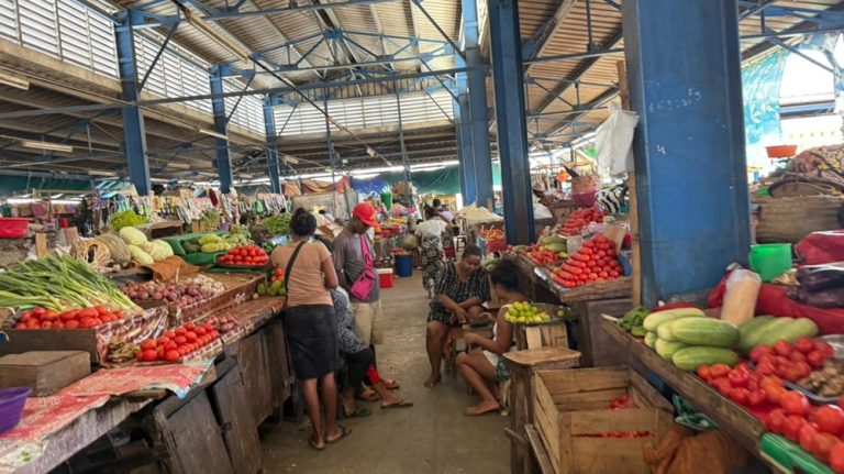 Marché couvert traditionnel à Madagascar avec étals de fruits, légumes et produits frais Caption : Description :