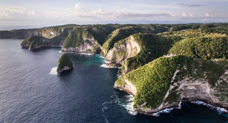 Panoramic aerial view featured in this Nusa Penida travel guide showing the island's dramatic southern coastline, cliffs, and turquoise bays
