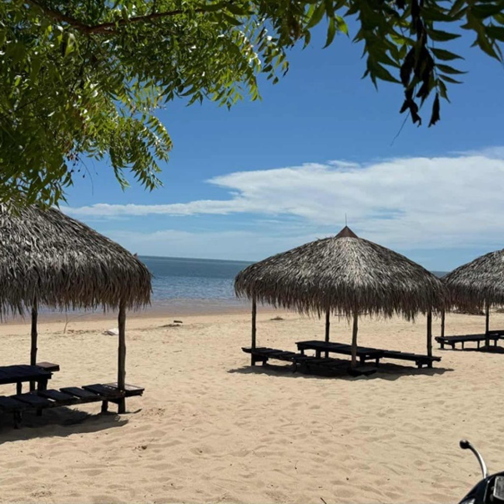 Conseils de voyage Madagascar : plage tropicale bordée de sable blanc et paillotes en bord de mer
