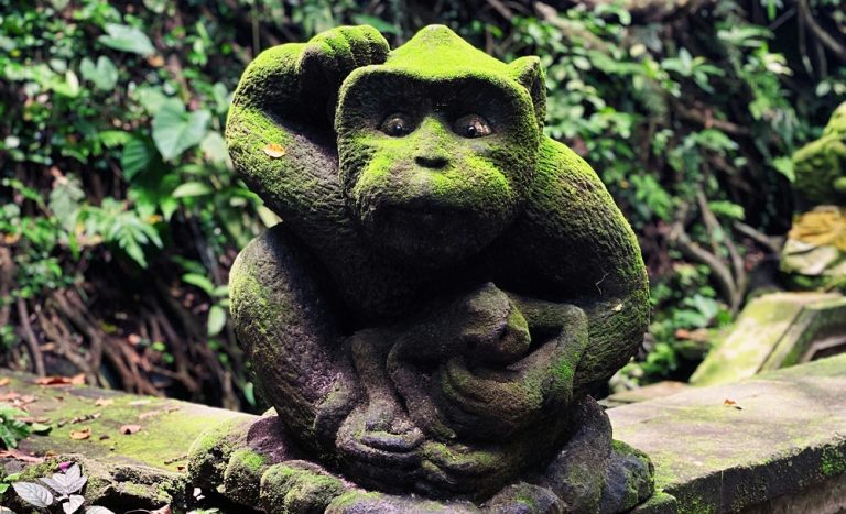 Ubud travel guide featuring a moss-covered monkey statue in the Sacred Monkey Forest Sanctuary, Ubud, Bali