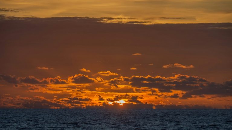 Canggu travel guide sunset over the Indian Ocean with dramatic clouds and golden evening light along Bali's west coast