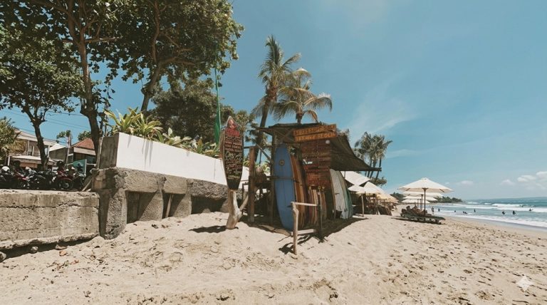 Canggu travel guide beach scene with surfboards, beachfront cafés, and surfers enjoying Bali's popular coastline