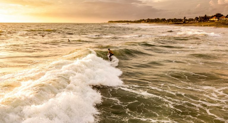 Surfer riding a wave at Berawa Beach during sunset on Bali's southwest coast Caption Description