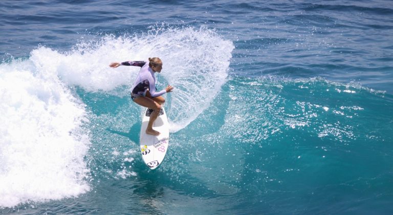 Surfer riding a turquoise wave in Bali's tropical waters during a surfing session