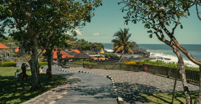 Visitors approaching Tanah Lot Temple along Bali's dramatic oceanfront coastline
