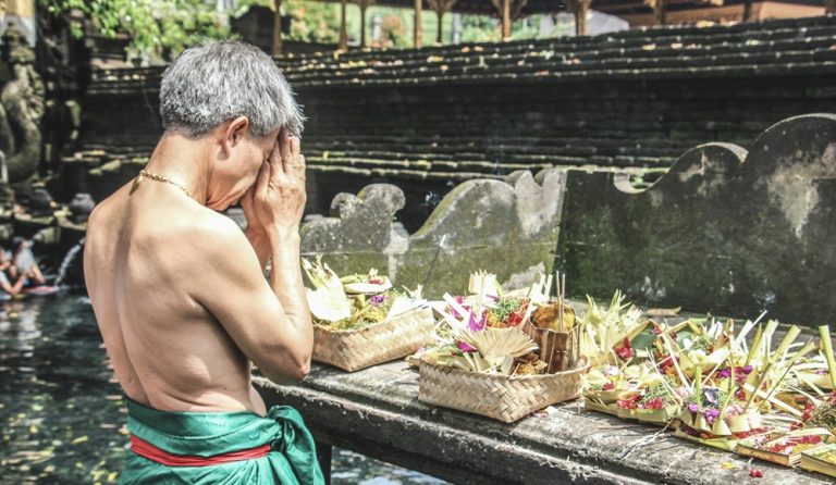 Ubud travel guide featuring a traditional purification ceremony at Tirta Empul Temple near Ubud, Bali Caption Description