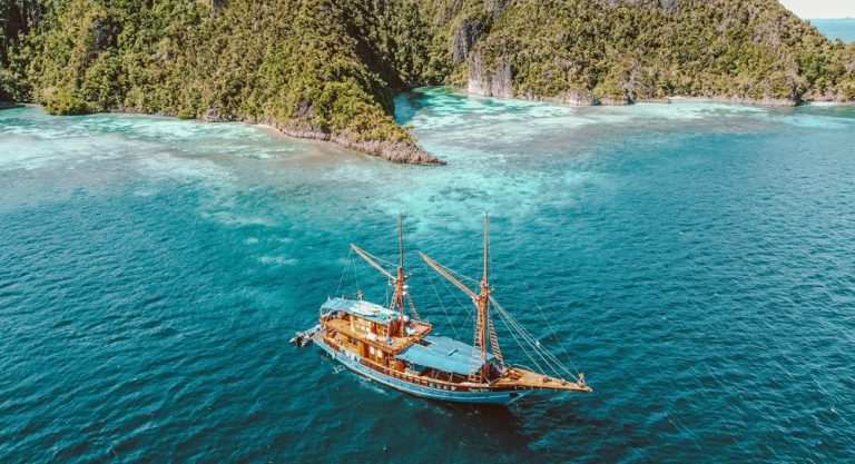 Traditional sailing boat cruising through clear turquoise waters near tropical islands