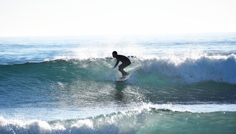 Surfer riding a clean wave in Bali during sunrise, featured in this Bali surf guide.
