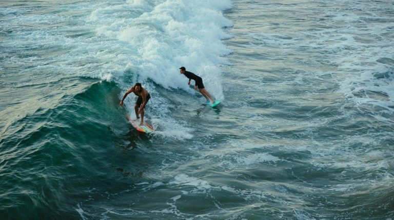 Two surfers riding the same wave in Bali, featured in this Bali surf guide.