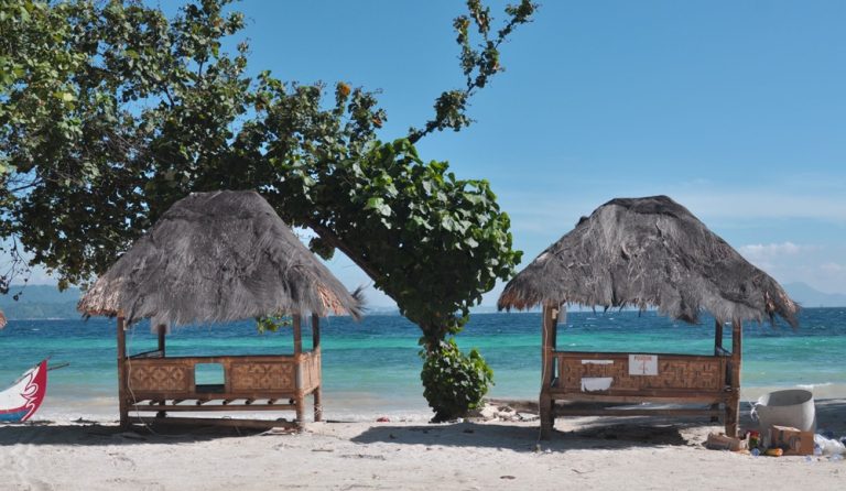 Traditional bamboo gazebos overlooking the turquoise waters of the Gili Islands, providing a shaded place to relax by the beach. Caption Description