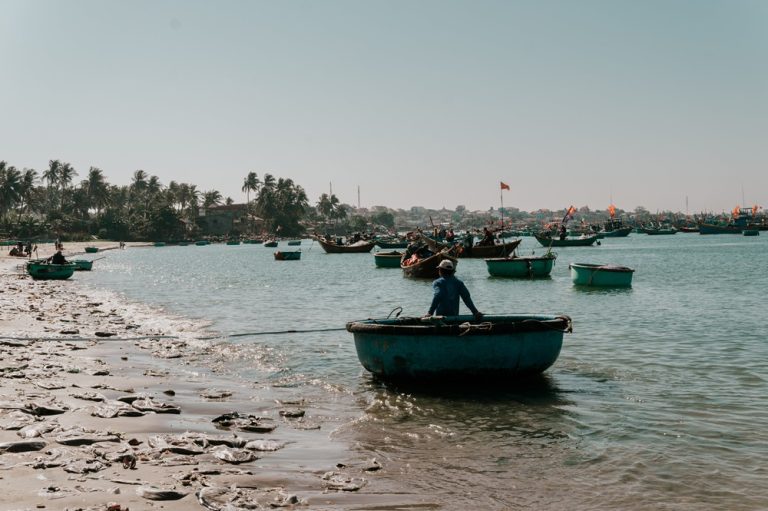 Traditional round basket boats and fishing boats along the coastline of Mui Ne in southern Vietnam Caption Description