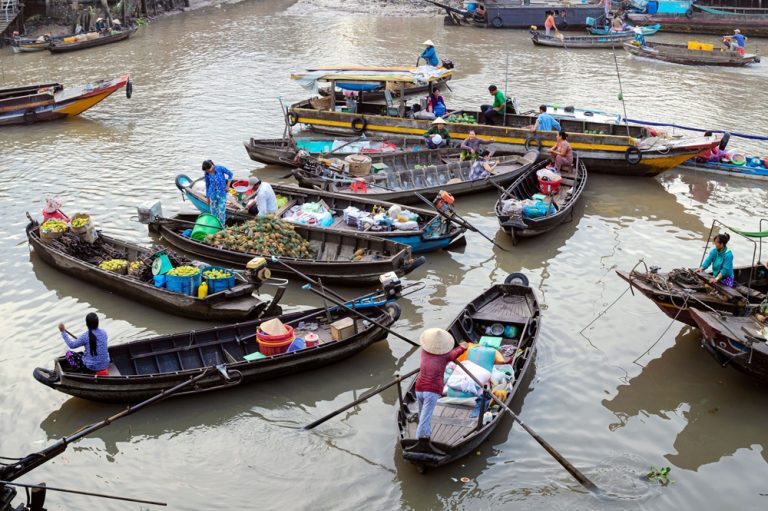 Traditional boats trading fruit and produce at a floating market in Can Tho, Mekong Delta, Vietnam