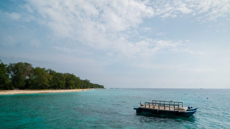 Traditional boat waiting off the coast near the Gili Islands, providing transfers between Lombok and the three islands. Caption Description