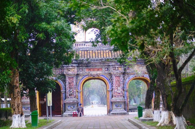Ornate gate leading into the Imperial City of Hue surrounded by ancient trees in central Vietnam