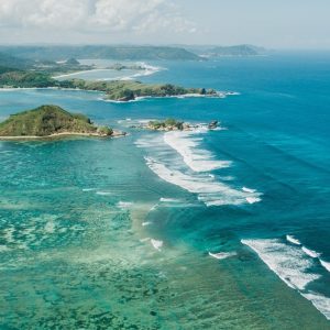 Kuta Lombok Travel Guide: Aerial view of Tanjung Aan Beach with turquoise water, white sand and the southern Lombok coastline.